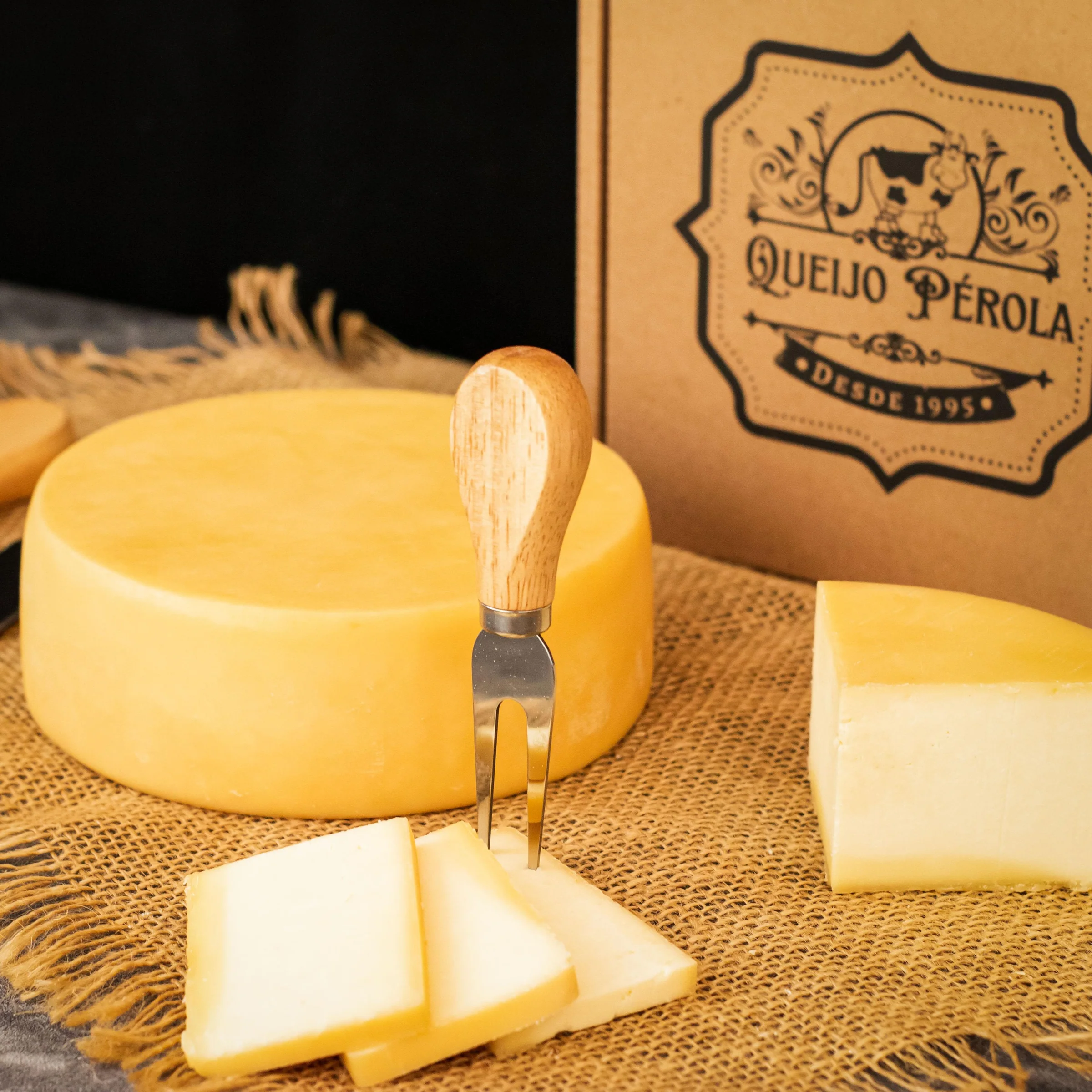 Queijo Pérola cortado em fatias sobre uma tábua de madeira