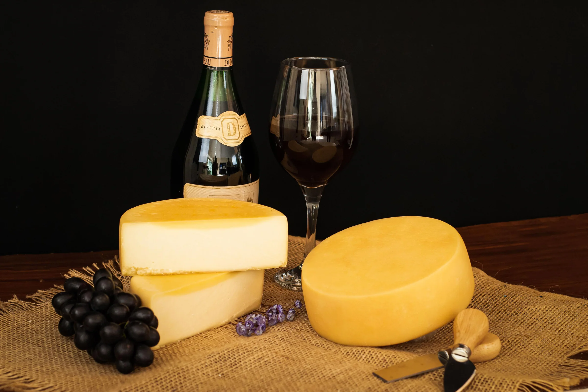 Queijos Pérola maturados servidos com vinho e uvas