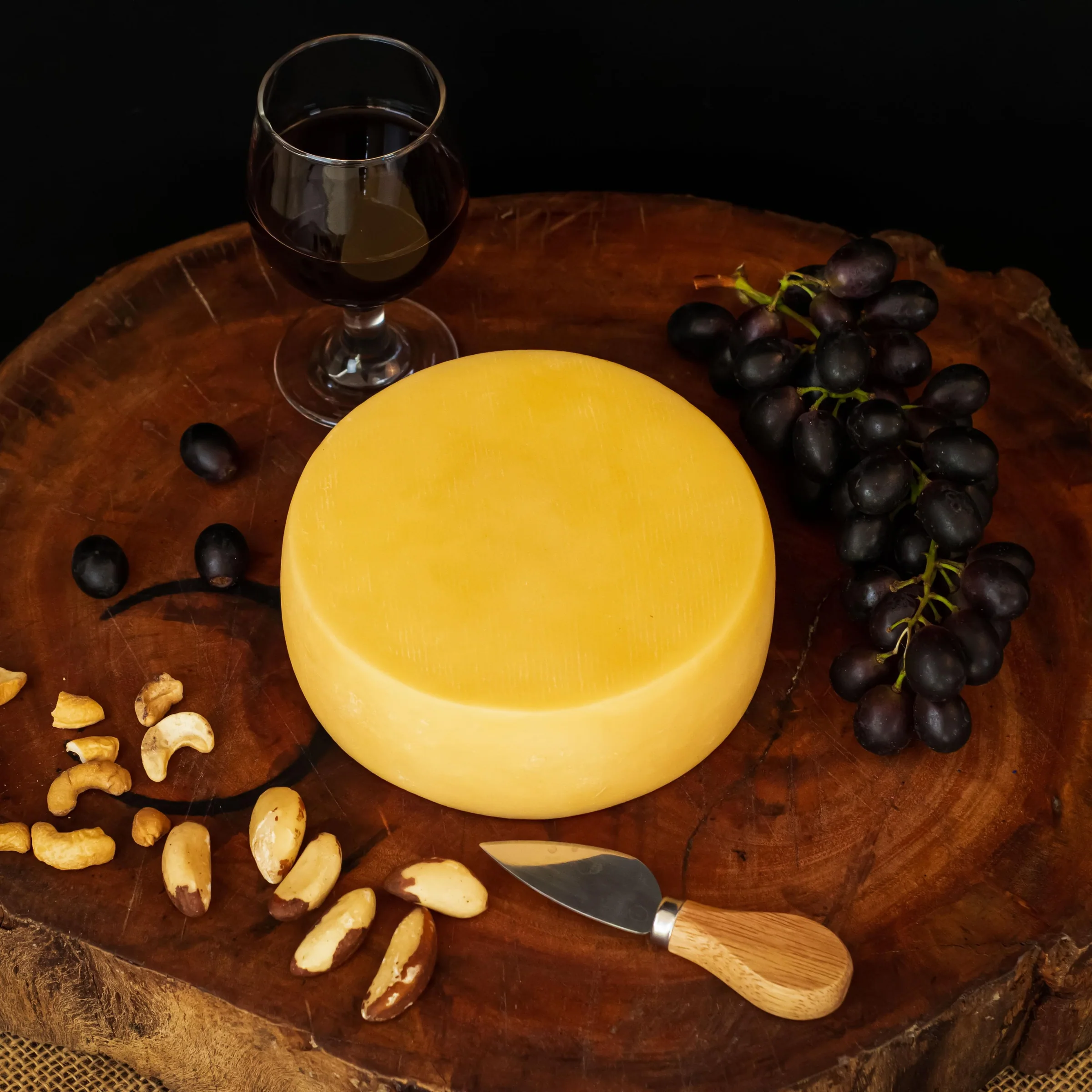 Queijo Pérola servido com vinho, uvas e castanhas